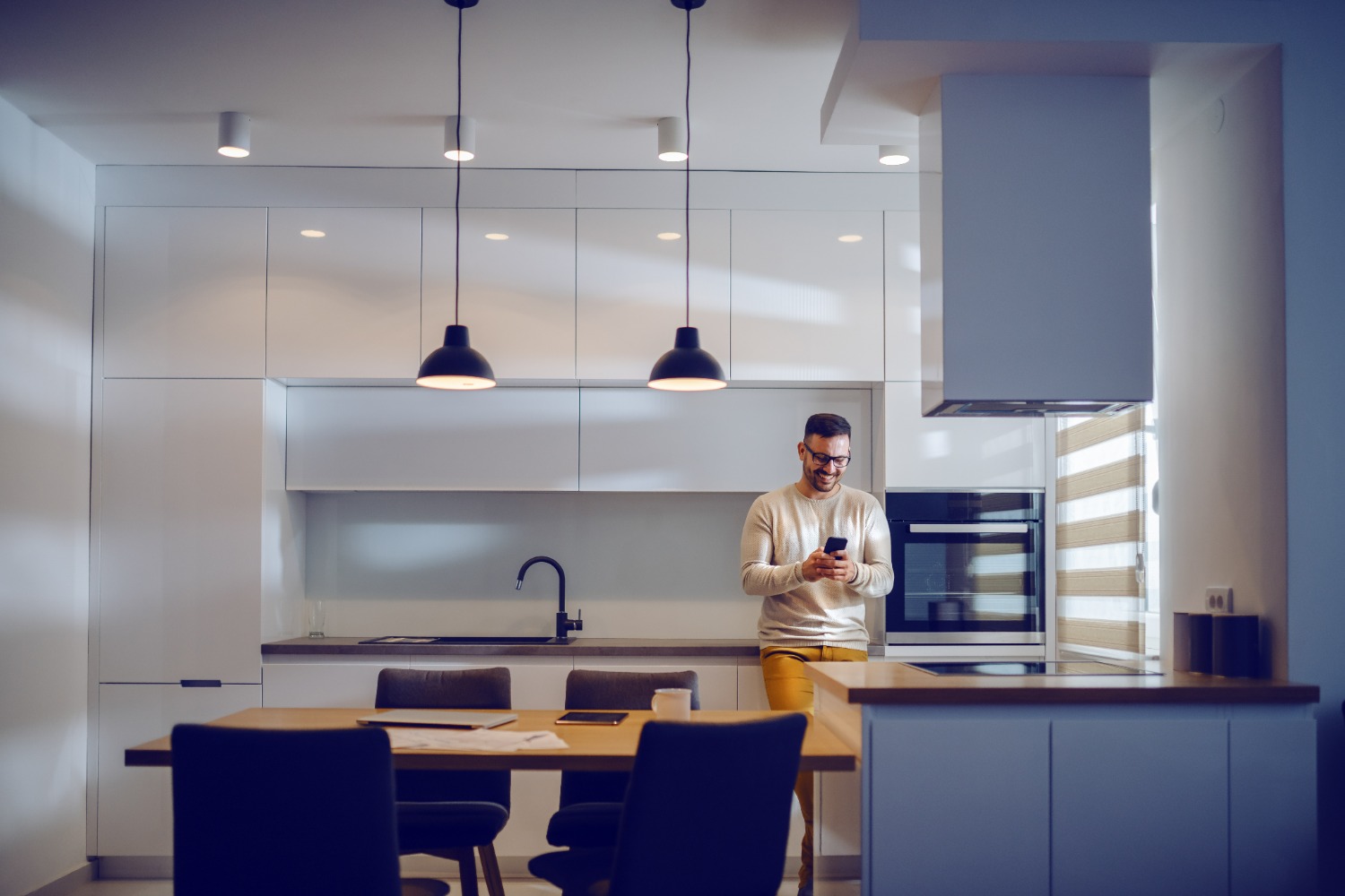 Man in kitchen looking at phone > HomeByMe Enteprise > Dassault Systèmes